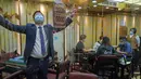 Staf yang mengenakan masker memperagakan langkah-langkah keamanan kepada media di ruang tamu mahjong di Hong Kong, Rabu (28/4/2021). Hong Kong akan kembali membuka bar dan klub malam, memperpanjang jam makan dan memungkinkan lebih banyak pengunjung per meja. (AP Photo/Kin Cheung)
