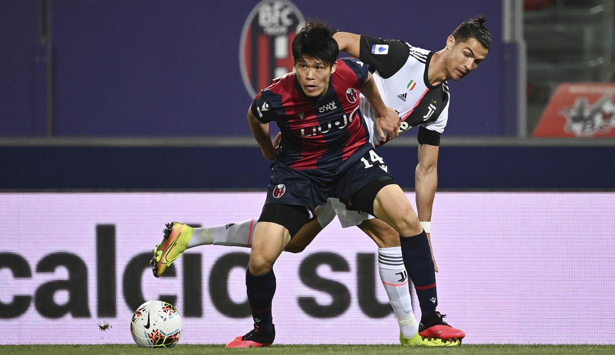 Striker Juventus, Cristiano Ronaldo, berebut bola dengan pemain Bologna, Takehiro Tomiyasu, pada laga Serie A di Stadion Renato Dall'Ara, Senin (22/6/2020). Juventus menang 2-0 atas Bologna. (AP/Massimo Paolone)