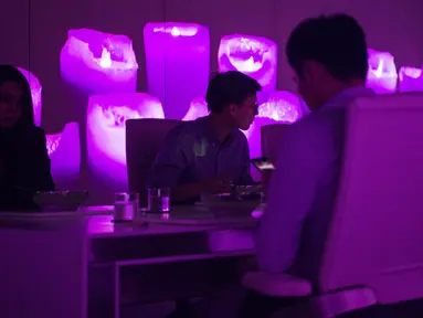 Pengunjung menikmati makan malam di sebuah ruangan Restoran Ultraviolet di pusat kota Shanghai, 11 Oktober 2017. Di restoran ini pengunjung mendapat pengalaman makan malam disoroti cahaya ultraviolet. (CHANDAN KHANNA / AFP)