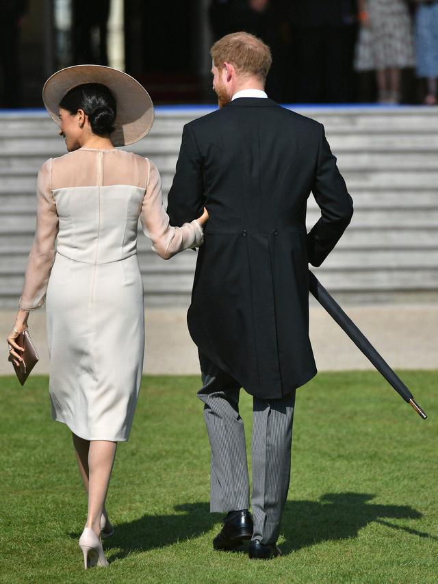 Duke dan Duchess of Sussex, Pangeran Harry dan Meghan Markle menghadiri pesta kebun Istana Buckingham di London, Selasa (22/5). Penampilan Meghan ini sekaligus merayakan ulang tahun ke-70 ayah mertuanya, Pangeran Charles. (Dominic Lipinski/Pool via AP)
