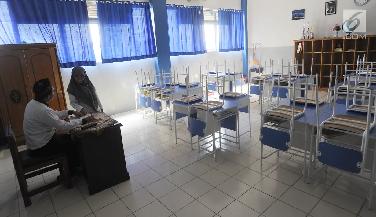 Guru berbincang dengan seorang siswa di ruang kelas yang kosong di Mts Annajah, Petukangan, Jakarta, Senin (5/8/2019). Masih padamnya listrik di sejumlah kawasan Jakarta membuat kegiatan belajar mengajar terganggu hingga memaksa pihak sekolah memulangkan siswa lebih awal. (merdeka.com/Arie Basuki)