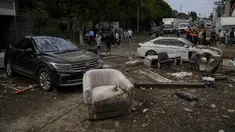Orang-orang berjalan di samping kendaraan dan perabotan yang berserakan pasca banjir akibat hujan lebat di Istanbul, Turki, RBu (6/9/2023). (AP Photo/Khalil Hamra)