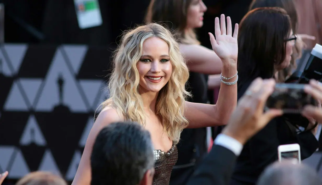 Aktris Jennifer Lawrence menyapa para fans saat tiba menghadiri Academy Awards ke 90 di Hollywood, California, AS (4/3). Jennifer Lawrence tampil cantik dan seksi dengan gaun blink-blink. (AFP Photo/Kyle Grillot)