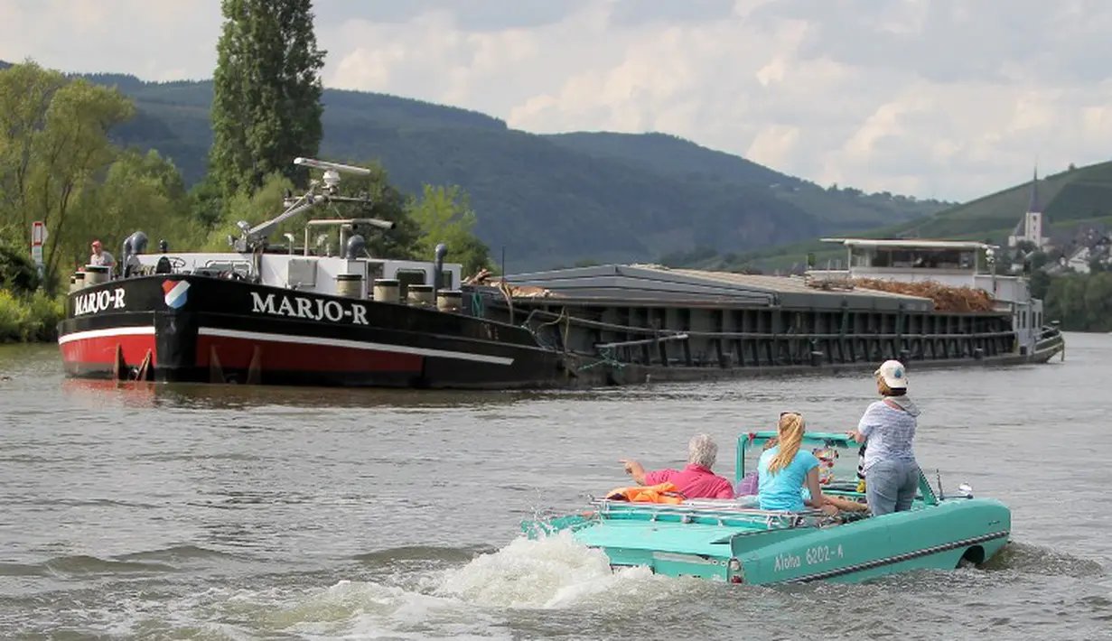 Sebuah mobil amphibi salah satu peserta reli "Amphib 2014" tampak melewati sebuah kapal yang sedang singgah di  sungai Mosel, Jerman, Minggu (3/8/2014)  (AFP PHOTO/Fredrik VON Erichse)