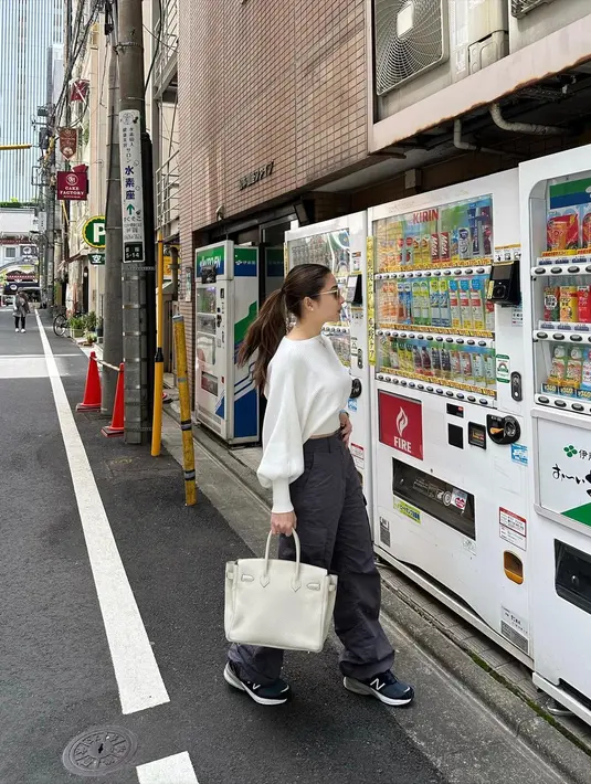 Tampil minimalis dengan blus panjang warna putih, loose pants abu-abu, dan hand bag putih. [Instagram/nikitawillyofficial94]
