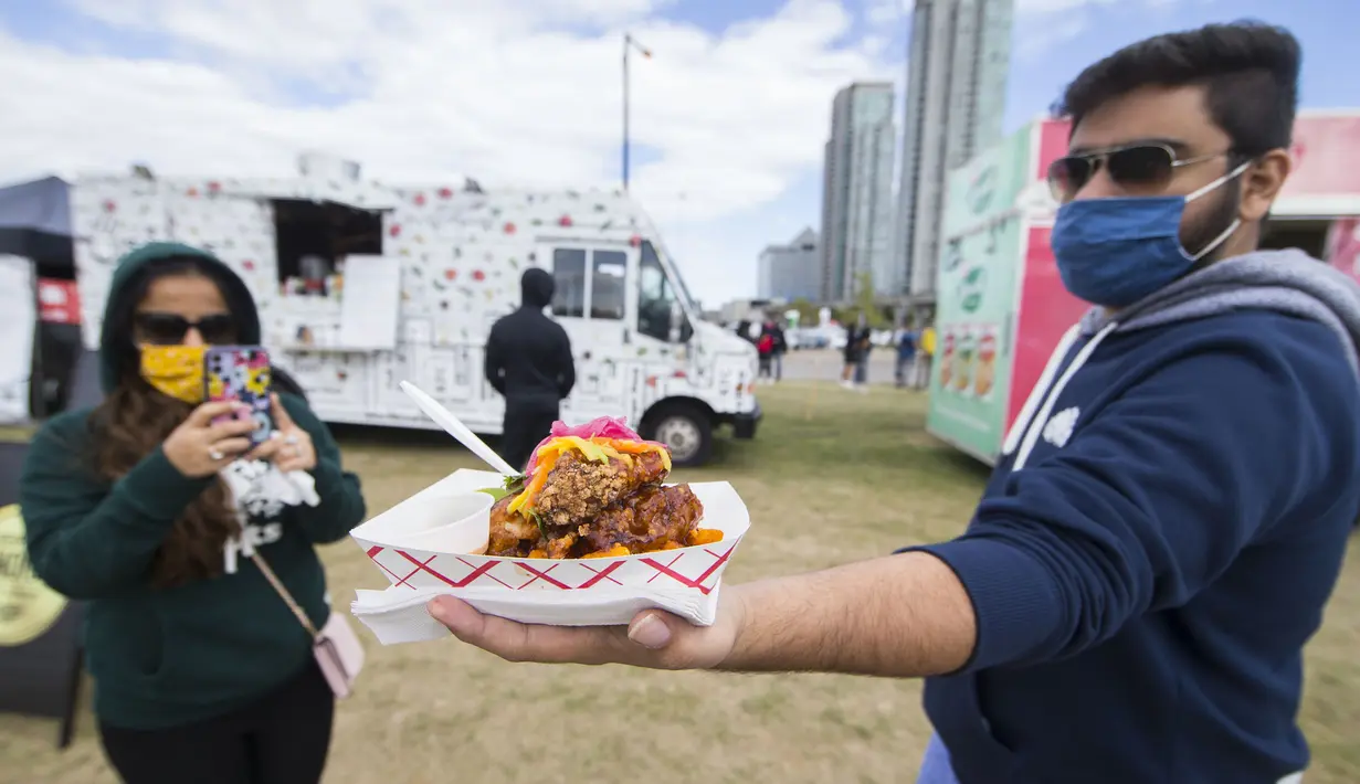 Seorang pria yang mengenakan masker memperlihatkan hidangan ayam goreng di Festival Ayam Goreng, Toronto, Kanada, 20 September 2020. Festival yang digelar di tengah pandemi COVID-19 tersebut berlangsung pada 19-20 September 2020 dengan menghadirkan sekitar 30 jenis ayam goreng. (Xinhua/Zou Zheng)