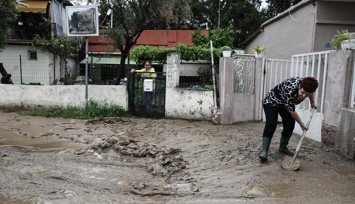 Sementara warga bekerja tanpa lelah untuk membersihkan jalan-jalan yang tersumbat setelah hujan deras. (Photo by Sakis MITROLIDIS / AFP)