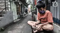 Seorang anak mengenakan masker saat bermain di depan rumah di RW 004, Cipinang Melayu, Jakarta, Rabu (27/1/2021). Pemprov DKI Jakarta mencatat sebanyak 54 rukun warga (RW) menjadi zona merah Covid-19 per 21 Januari 2021. (merdeka.com/Iqbal S Nugroho)