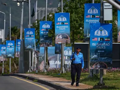 Seorang petugas polisi berjalan melewati papan reklame di dekat Hotel Serena menjelang putaran kedua negosiasi antara Amerika Serikat dan Iran, di Islamabad, Pakistan, Selasa 21 April 2026. Pemerintah Pakistan saat ini tengah meningkatkan penjagaan keamanan di wilayah Islamabad secara besar-besaran. (AP Photo/Anjum Naveed)