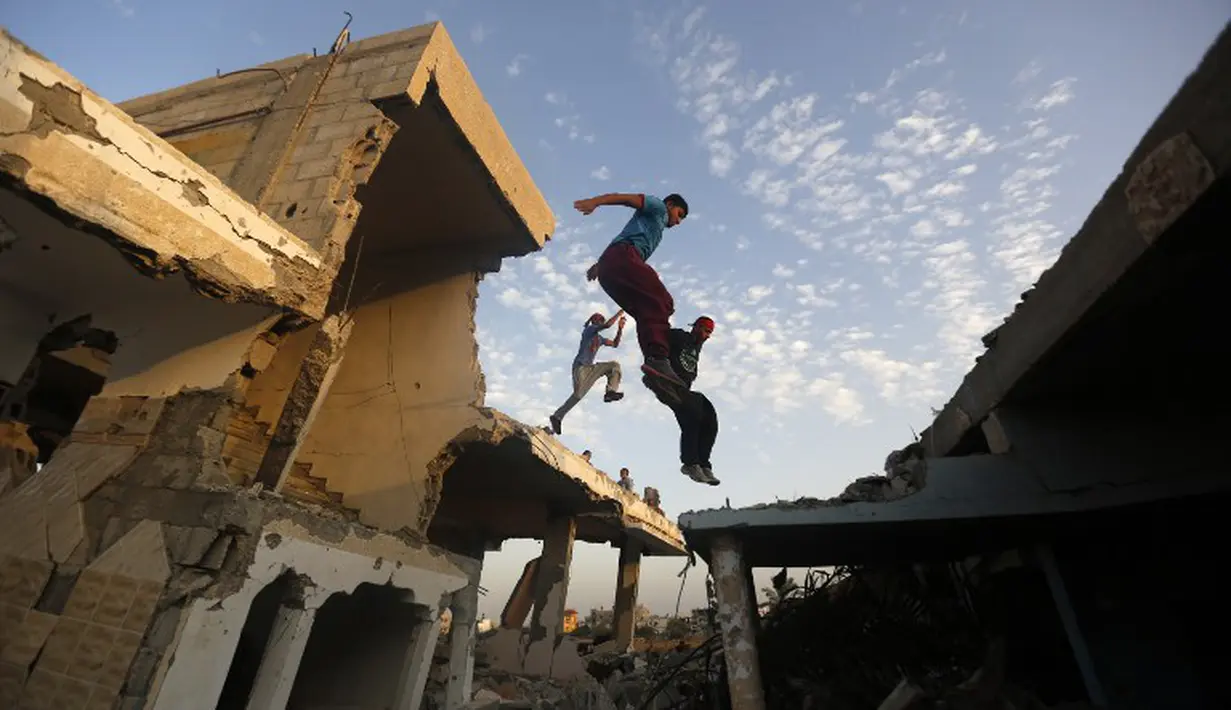 Aksi Parkaour remaja Palestina di bekas gedung yang hancur akibat serangan roket Israel. Foto diambil pada Jumat (14/11/2014) (AFP Photo/Mohammed Abed)