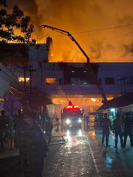 Petugas pemadam kebakaran bekerja untuk menyelamatkan orang yang mencoba melarikan diri dari kebakaran di hotel-kasino Grand Diamond City di Poipet pada 29 Desember 2022. Sebanyak 10 orang tewas dalam kebakaran di hotel-kasino Kamboja di perbatasan Thailand, polisi kata 29 Desember. (AFP/STR)