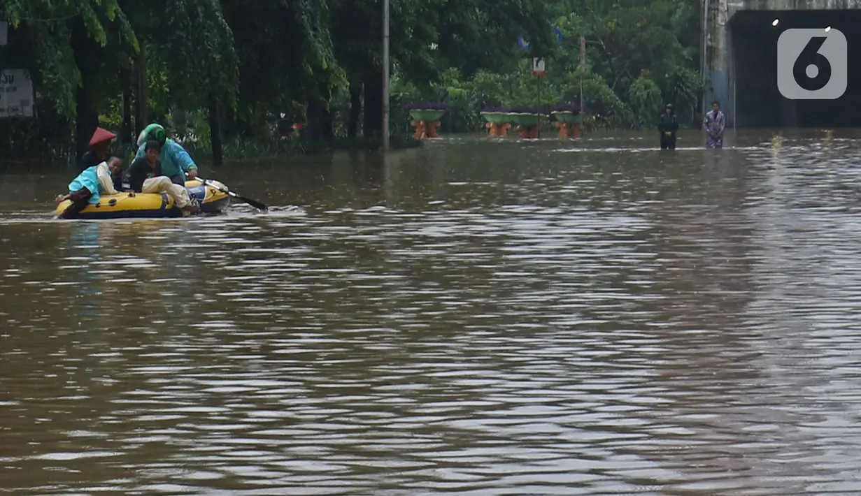 Warga menaiki perahu karet saat melintasi kawasan DI Panjaitan, Jakarta, Selasa (25/2/2020). Hujan yang mengguyur Jakarta sejak dini hari tadi membuat kawasan tersebut terendam banjir sehingga tak bisa dilintasi kendaraan bermotor. (Liputan6.com/Herman Zakharia)