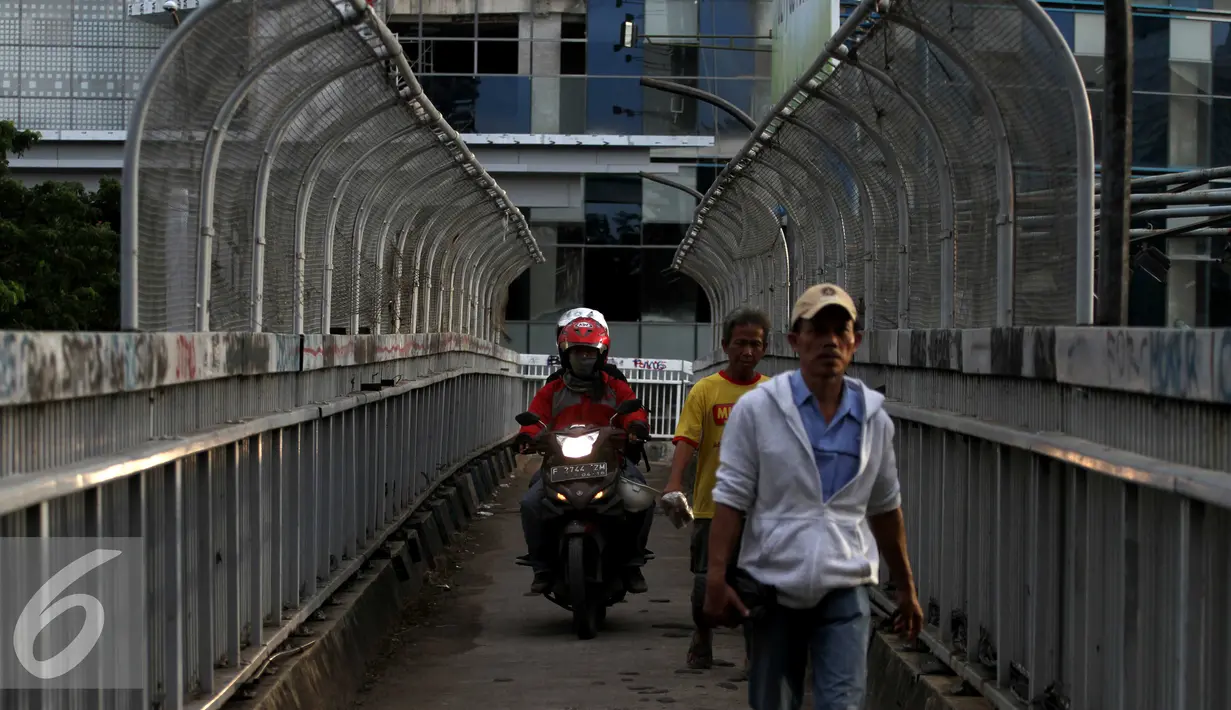 Pejalan kaki dan pemotor melintas di atas JPO di kawasan Grogol, Jakarta, Rabu (4/5). JPO yang seharusnya diperuntukkan bagi pejalan kaki itu kini sering dimanfaatkan pengendara motor untuk jalan pintas. (Liputan6.com/Gempur M Surya)