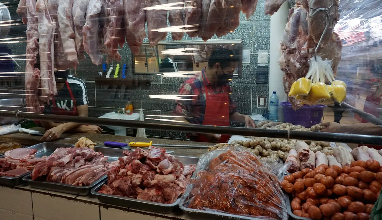 Seorang tukang daging menunggu pelanggan dari balik sekat tirai pelindung plastik di pasar La Asuncion di Villa Nueva, Guatemala City pada 20 Juli 2020. Kios di pasar itu menggunakan tirai pelindung plastik untuk menjaga jarak fisik guna mengurangi resiko penyebaran virus Corona. (Johan ORDONEZ/AFP)