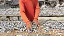 Pekerja menjemur ikan asin di Jakarta, Minggu (6/2/2022). Pengusaha ikan asin di daerah tersebut mengaku mengurangi produksinya karena permintaan pasar sedang turun dan terkendala proses pengeringan akibat curah hujan. (Liputan6.com/Angga Yuniar)