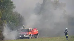 Petugas memadamkan api di hutan yang terbakar di Cissac-Medoc, Prancis, Kamis (21/4). Penyebab kebakaran masih dalam tahap penyelidikan. (PHOTO PHOTO / MEHDI FEDOUACH)