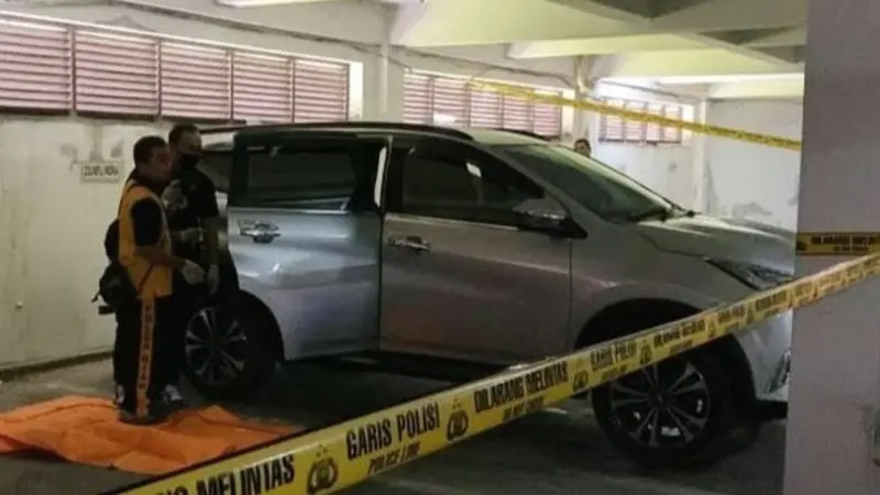 Polisi memasang garis di mobil tempat mayat ditemukan di basement DPRD Riau.