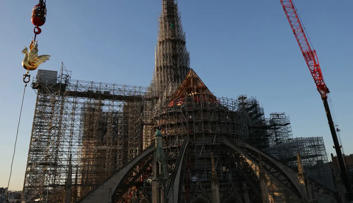 Ayam jago emas baru berisi relik diangkat dengan derek untuk dipasang di puncak menara Katedral Notre Dame sebagai bagian dari rekonstruksi, di pusat kota Paris, Sabtu (16/12/2023). (Thomas SAMSON / AFP)
