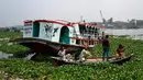 Orang-orang menonton feri yang diselamatkan setelah kecelakaan di Sungai Shitalakshya di Narayanganj, Bangladesh (21/3/2022). Feri ML Afsar Uddin tenggelam di sungai setelah ditabrak kapal kargo. (AFP/Munir uz Zaman)