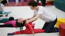 Guru melatih salah seorang murid selama kelas senam di sekolah atletik Shanghai Yangpu Youth Amateur, China (18/5). Latihan keras ini bisa membuat anak-anak menangis dan cedera ini diharapkan mampu menjadikan atlet berkualitas. (REUTERS/Aly Song)