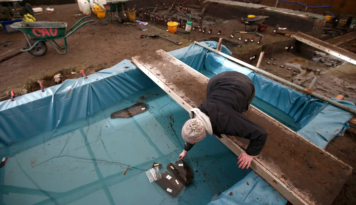 Arkeolog memisahkan penemuan ke dalam wadah khusus. di lokasi situs penemuan rumah zaman Perunggu di Peterborough, Inggris (12/1). Rumah ini diduga hancur akibat api dan kemudian ambruk ke sungai. (REUTERS/Peter Nicholls)