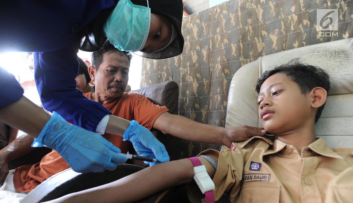 Seorang anak diambil sampel darah di RT1-2/1 Kelurahan Cinere, Depok, Rabu (28/6/2019). Dinas Kesehatan Depok dan Puskesmas Cinere melakukan investigasi sumber penyakit dan sampel darah warga di kawasan ini terkait sudah lebih dari sepekan 12 warga terjangkit hepatitis A. (merdeka.com/Arie Basuki)