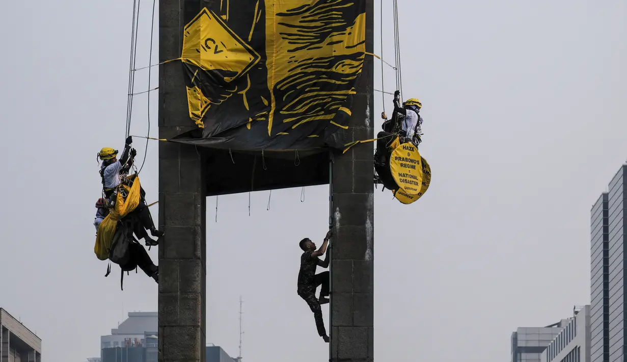 Seorang personel militer Indonesia memanjat Patung Selamat Datang untuk menurunkan aktivis Greenpeace Indonesia yang melakukan aksi protes di kawasan Bundaran Hotel Indonesia, Jakarta, Selasa (20/10/2026). Aksi tersebut digelar bertepatan dengan dua tahun pelantikan Presiden Prabowo Subianto. Para aktivis mendesak pemerintah mengambil langkah nyata untuk mengatasi krisis iklim yang kian memburuk serta kenaikan biaya hidup. (BAY ISMOYO/AFP)