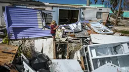 Seorang wanita berjalan melewati puing-puing rumah yang hancur di Pulau Matlacha di Lee County Florida pada 7 November 2022. Badai subtropis Nicole yang langka dapat menghantam pantai timur Florida minggu ini ketika penduduk berusaha pulih dari Badai Ian yang mematikan. (AFP/ Giorgio Viera)