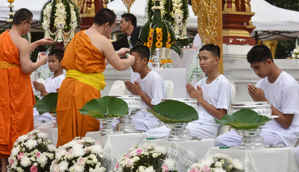 Biksu mencukur rambut anak-anak, yang diselamatkan dari gua di Thailand, pada upacara pentahbisan di Kuil Wat Phra That Doi Wao, Chiang Rai, Selasa (24/7). 11 dari 12 remaja itu menjalani ritual menjadi biksu. (Panumas Sanguanwong/THAI NEWS PIX/AFP)
