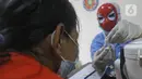 Tenaga kesehatan bertopeng superhero memperlihatkan botol vaksin covid-19 kepada orang tua anak saat vaksinasi anak usia 6-11 tahun di RSIA Tambak, Jakarta, Rabu (22/12/2021). Penggunaan topeng superhero dimaksudkan menarik minat anak-anak yang mengikuti vaksinasi. (lLiputan6.com/Herman Zakharia)