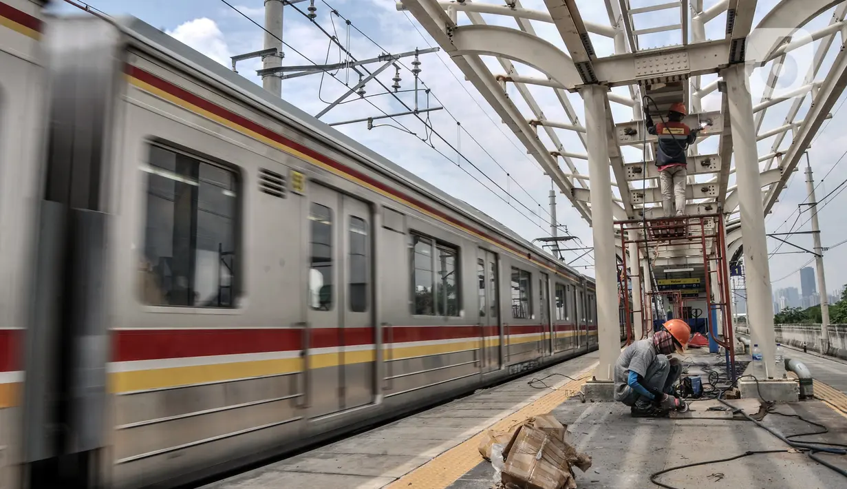 Kereta melintas saat pekerja menyelesaikan pembangunan Stasiun Matraman, Jakarta Timur, Kamis (23/12/2021).  Stasiun Matraman yang berada antara Stasiun Manggarai dan Jatinegara ini diharapkan dapat memecah kepadatan penumpang di kedua stasiun tersebut. (merdeka.com/Iqbal S. Nugroho)