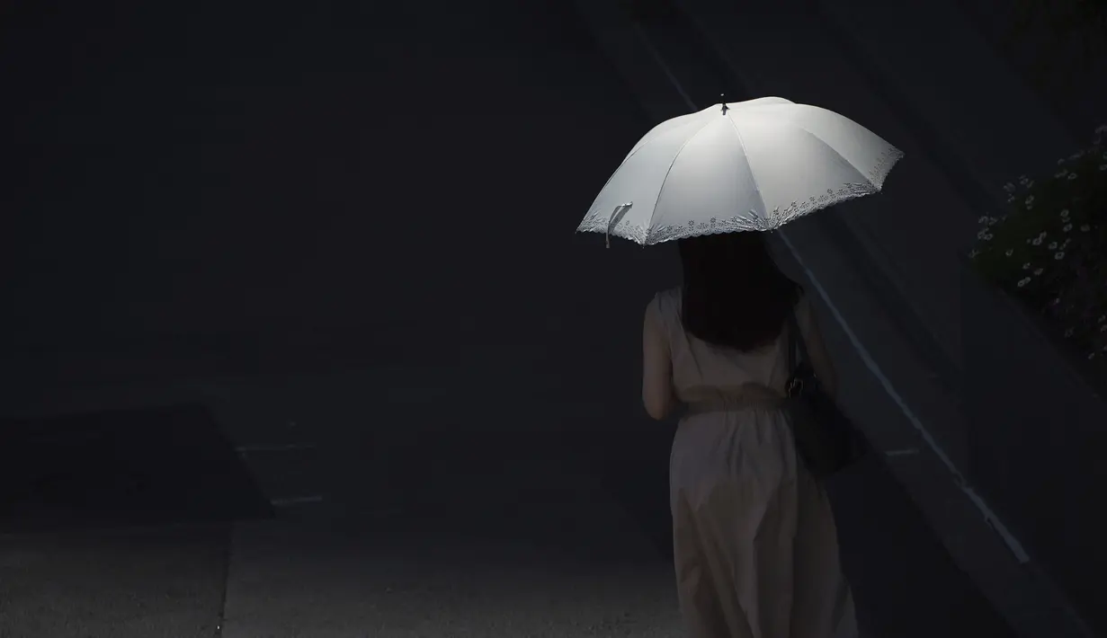 Seseorang berjalan dengan payung di bawah terik matahari di Tokyo, Senin (30/5/2022). Cuaca panas pada hari Senin telah ditetapkan dengan suhu naik lebih dari 27 derajat Celcius (80,6 derajat Fahrenheit) di Tokyo, menurut Badan Meteorologi Jepang. (AP Photo/Eugene Hoshiko)