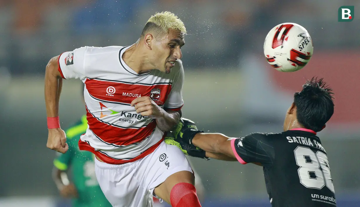 Bek Madura United, Jaimerson Xavier (kiri) berduel udara dengan kiper Persebaya Surabaya, Satria Tama dalam laga matchday ke-2 Grup C Piala Menpora 2021 di Stadion Si Jalak Harupat, Bandung, Minggu (28/3/2021). Madura United kalah 1-2 dari Persebaya. (Bola.com/M Iqbal Ichsan)