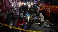 Orang-orang yang terluka ditolong di jalan dekat tempat kejadian di Seoul, Korea Selatan, Minggu pagi (30/10/2022). Puluhan orang mengalami henti jantung setelah ribuan orang berdesakan di sebuah gang di kawasan Itaewon untuk merayakan Halloween pada Sabtu malam. (AP Photo/Lee Jin-man)