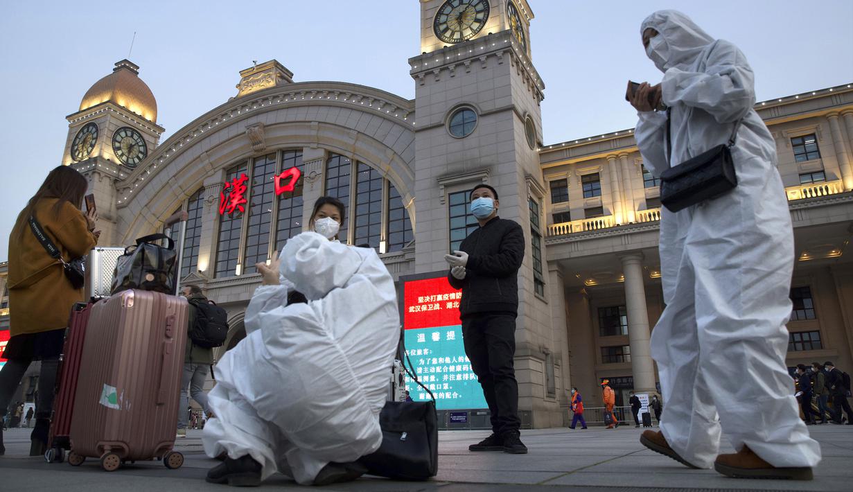 Penumpang yang mengenakan pakaian pelindung berkumpul di luar Stasiun Hankou, Wuhan, Provinsi Hubei, China, Rabu (8/4/2020). Setelah 11 minggu lockdown, layanan kereta di kota yang menjadi titik awal pandemi virus corona COVID-19 ini kembali beroperasi. (AP Photo/Ng Han Guan)