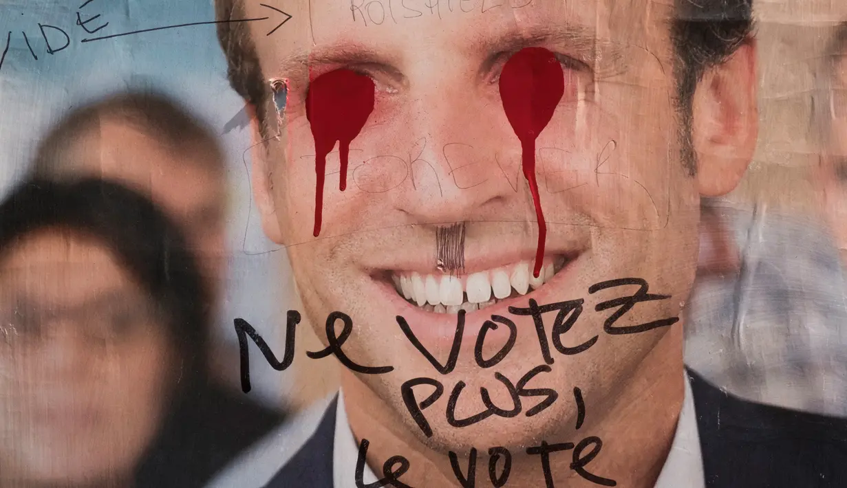 Poster Capres Prancis,  Emmanuel Macron terlihat rusak di Paris, Selasa (2/5). Sejumlah poster capres Prancis lainnya juga tampak rusak yang diduga dilakukan oleh orang yang tidak suka dengan mereka. (AFP PHOTO / JOEL SAGET)