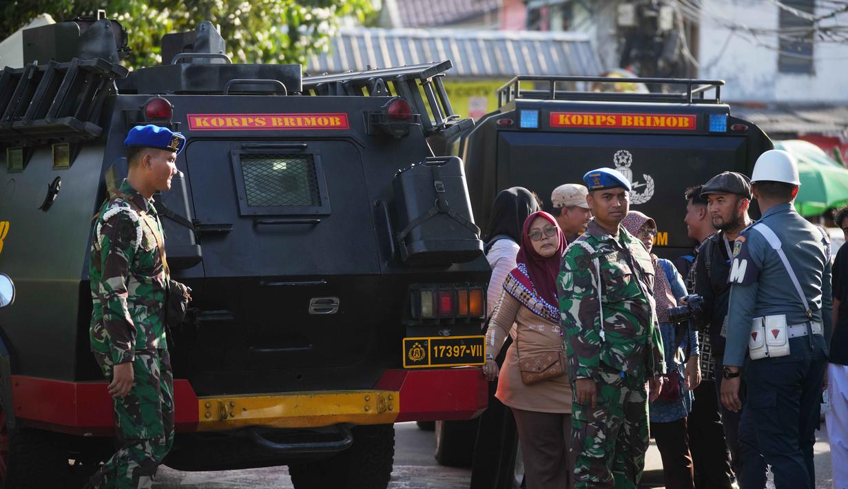 Sementara, ledakan kedua menyusul beberapa menit kemudian dari area belakang kantin sekolah. Tampak dalam foto, warga yang penasaran menyaksikan personel militer berjaga-jaga di dekat SMAN 72 Jakarta pada Jumat 7 November 2025. (AP Photo/Dita Alangkara)