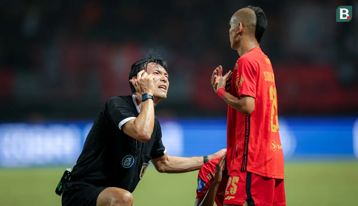 Wasit asal Jepang, Futoshi Nakamura (kiri), berdialog menggunakan bahasa isyarat dengan pemain Persija Jakarta, Riko Simanjuntak, saat pertandingan pekan ke-23 BRI Liga 1 2023/2024 antara Persija Jakarta melawan PSS Sleman yang berlangsung di Stadion Patriot Chandra Bhaga, Bekasi, Sabtu (16/12/2023). Futoshi Nakamura juga terlihat sering melakukan komunikasi dengan pemain yang membuat timbul rasa respek. (Bola.com/Bagaskara Lazuardi)