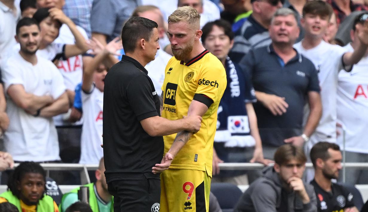 Striker Sheffield United, Oli McBurnie berbicara dengan pelatih Paul Heckingbottom setelah mendapat kartu merah saat menghadapi Tottenham Hotspur pada laga pekan kelima Premier League 2023/2024 di Tottenham Hotspur Stadium, London, Sabtu (16/9/2023) malam WIB. (AFP/Justin Tallis)