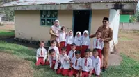 Guru dan Murid SDN 002 Desa Tanjung, Kecamatan Koto Kampar Hulu, Kabupaten Kampar, Riau, yang belajar di bekas WC karena tidak ada ruangan lagi. (Liputan6.com/M Syukur)