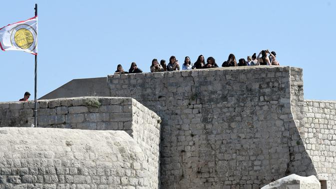 Wisatawan mengambil gambar dari atas benteng saat mengunjungi kota tua Dubrovnik di Kroasia pada 28 Maret 2019. Dubrovnik  yang telah dianugerahi UNESCO sebagai warisan dunia menjadi salah satu hal yang menjadi daya tarik wisatawan ke kota yang dikelilingi pulau ini. (Denis LOVROVIC / AFP)