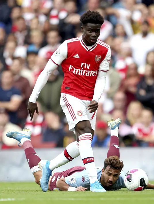 Pemain Arsenal, Bukayo Saka menggiring bola dari kawalan gelandang Aston Villa, Trezeguet selama pertandingan lanjutan Liga Inggris di Stadion Emirates, London (22/9/2019). Arsenal menang tipis atas Aston Villa 3-2. (AP Photo/Steven Paston)