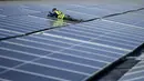 <p>Pekerja memperbaiki panel surya di pabrik fotovoltaik terapung di danau Silbersee di Haltern, Jerman barat (22/4/2022). Taman surya terapung terbesar di Jerman saat ini sedang dibangun dan akan menghasilkan hampir tiga juta kilowatt jam listrik per tahun. (AFP/Ina Fassbender)</p>