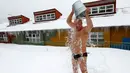 Seorang anggota klub perenang musim dingin yang bernama Leonid Gorbunov menyiramkan seember air dingin ke tubuhnya saat perayaan hari Polar Bear atau Beruang Kutub di kebun binatang Royev Ruchey, Krasnoyarsk, Rusia (27/11). (Reuters/Ilya Naymushin)