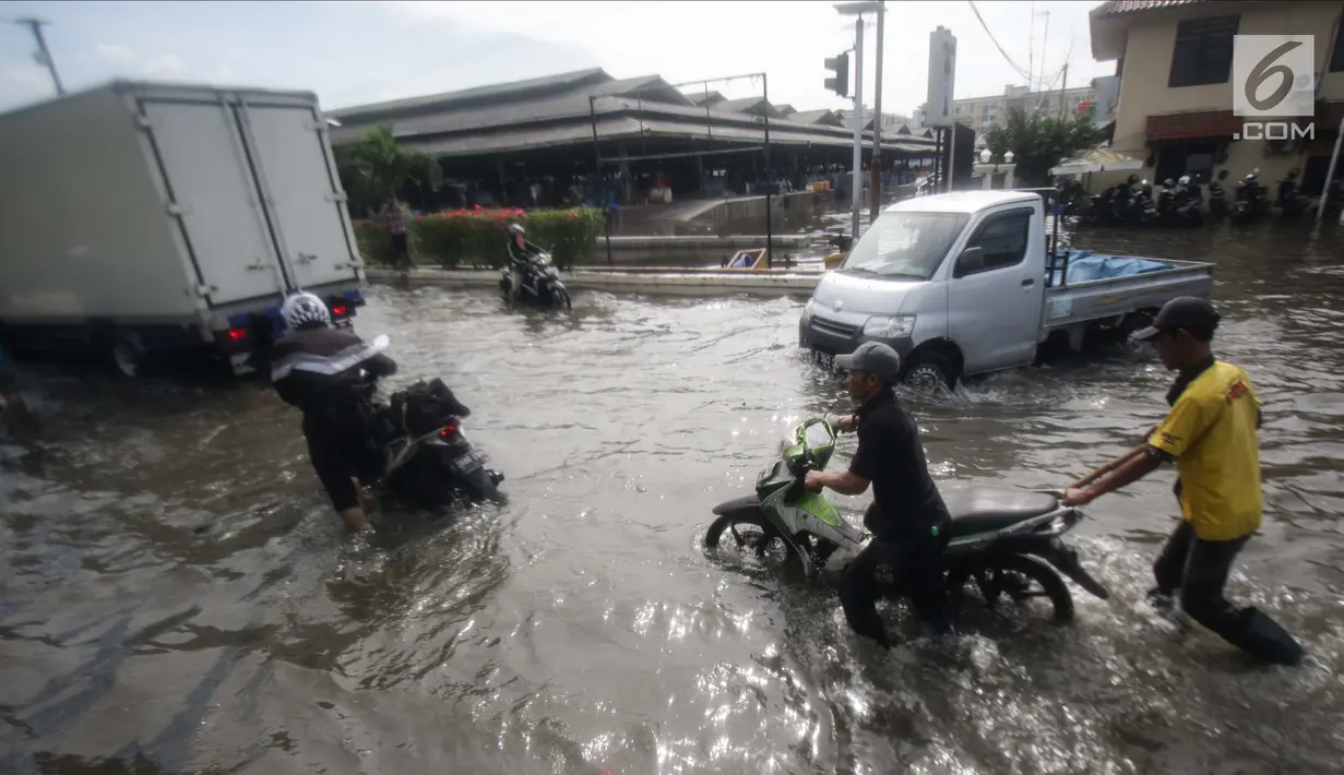 Pengendara mendorong motornya saat melintasi banjir rob di kawasan Muara Baru, Jakarta, Rabu (6/11). Banjir rob yang menggenangi kawasan ini setinggi 50 cm hingga 70 cm. (Liputan6.com/Faizal Fanani)