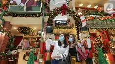 Pengunjung berswafoto berlatar belakang dekorasi Natal di atrium Lippo Mall Puri, Jakarta Barat, Sabtu (19/12/2020). Menyambut Hari Raya Natal dan Tahun Baru Lippo Mall Puri menampilkan dekorasi santa gift shop decoration dan santa home decoration. (Liputan6.com/Fery Pradolo)