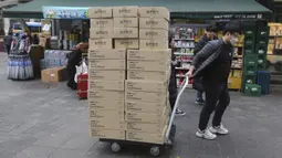 Seorang pekerja membawa kotak-kotak berisi masker ke apotek di sebuah distrik perbelanjaan di Seoul, Korea Selatan (28/1/2020). Penyebaran wabah virus corona berimbas pada peningkatan penjualan masker pelindung, sehingga bisnis ini berkembang pesat di Asia. (AP Photo/Ahn Young-joon)