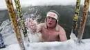 Seorang pria keluar dari air es setelah berenang selama hari yang membekukan di kota Omsk di Siberia, Rusia, Sabtu (26/12/2020). Suhu di Omsk turun hingga -32 derajat Celcius atau -25,6 derajat Fahrenheit. (AP Photo/Evgeniy Sofiychuk)