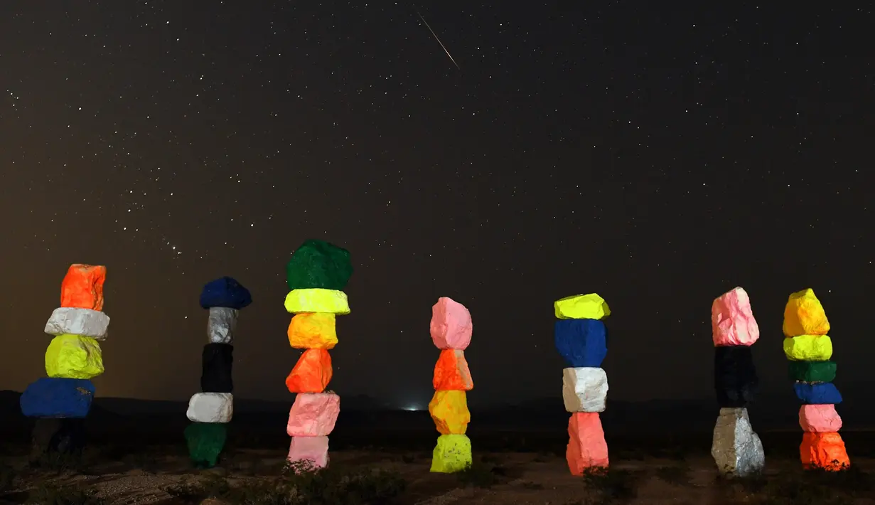 Meteor Perseid melintasi langit di atas instalasi seni "Seven Magic Mountains" dekat Jean, Nevada (13/8). Instalasi seni Seven Magic Mountains terdiri dari tujuh pilar batu-batu berwarna yang ditumpuk lebih dari 30 kaki tingginya. (AFP Photo/Ethan Miller)
