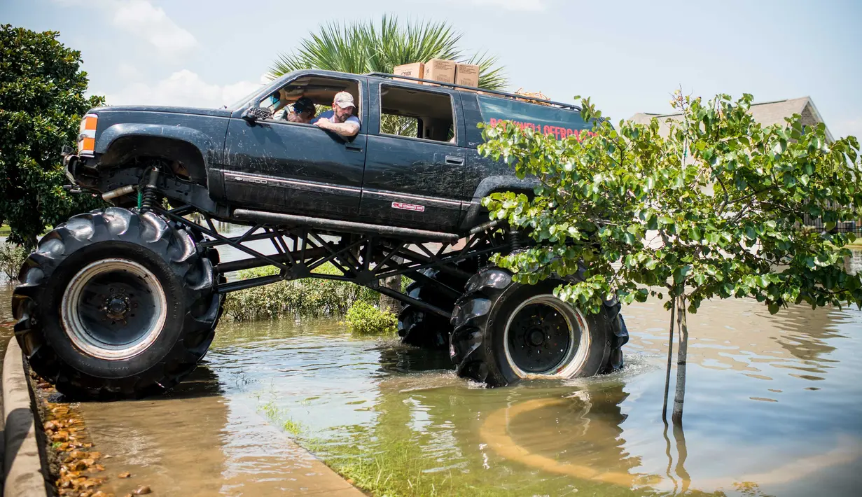 Truk monster menerobos genangan air saat membantu warga yang menjadi korban Badai Harley di Port Arthur, Texas, AS (1/9). Truk raksasa ini menjadi salah satu kendaraan yang diandalkan usai Badai Harley menghantam Texas. (AFP Photo/Emily Kask)